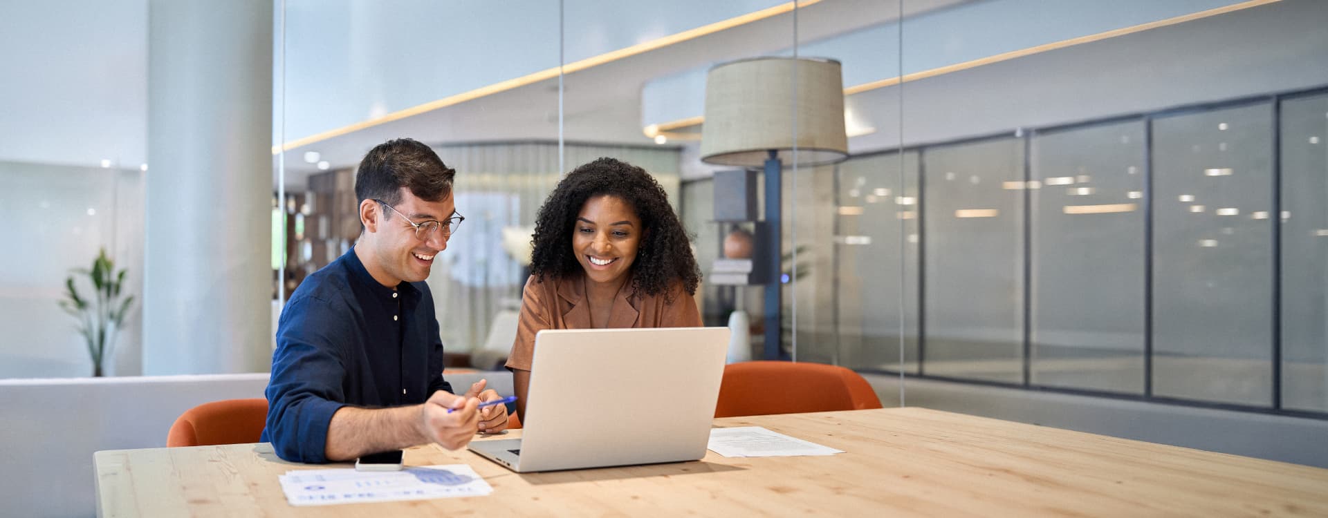 Two colleagues reviewing candidate profiles together on a laptop in a modern office